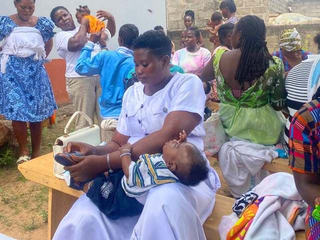 A HERO Network volunteer holding a baby during a community immunisation mobilisation session